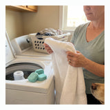 Pet owner checking a towel beside a washer and mint washer cleaner tablets