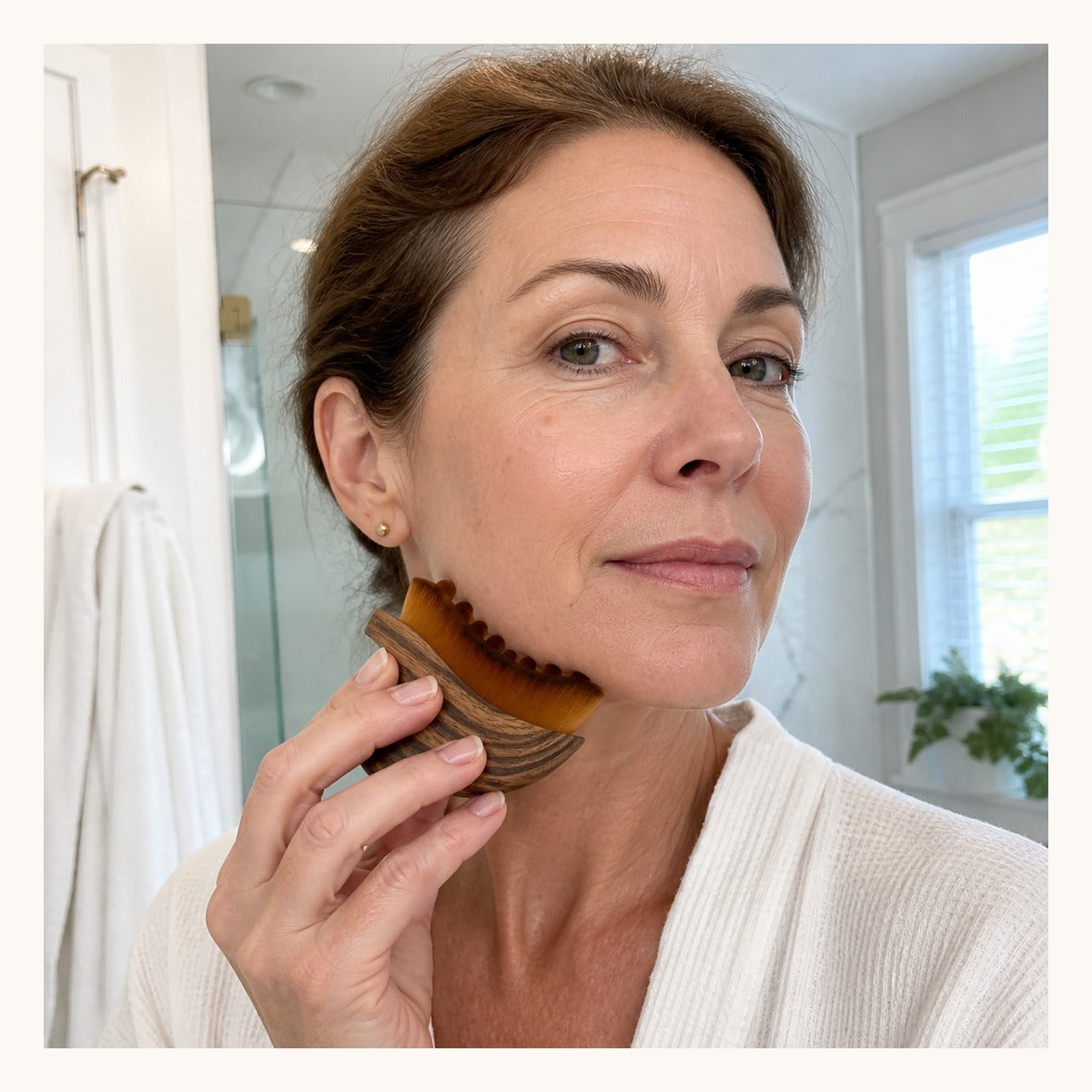 Mature woman gently using the brown Glowlift brush along her jawline