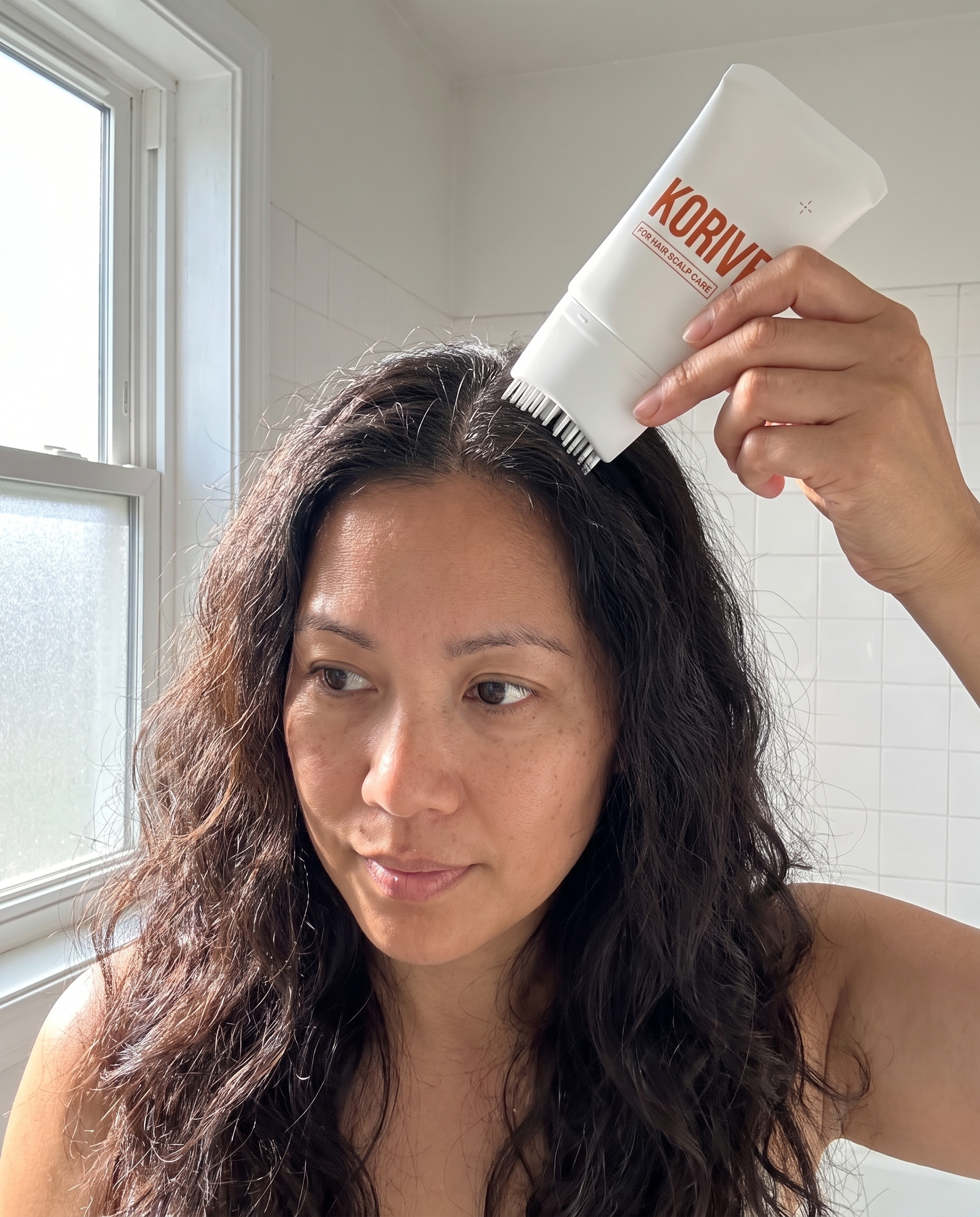 Korive brush serum applied along a scalp part line